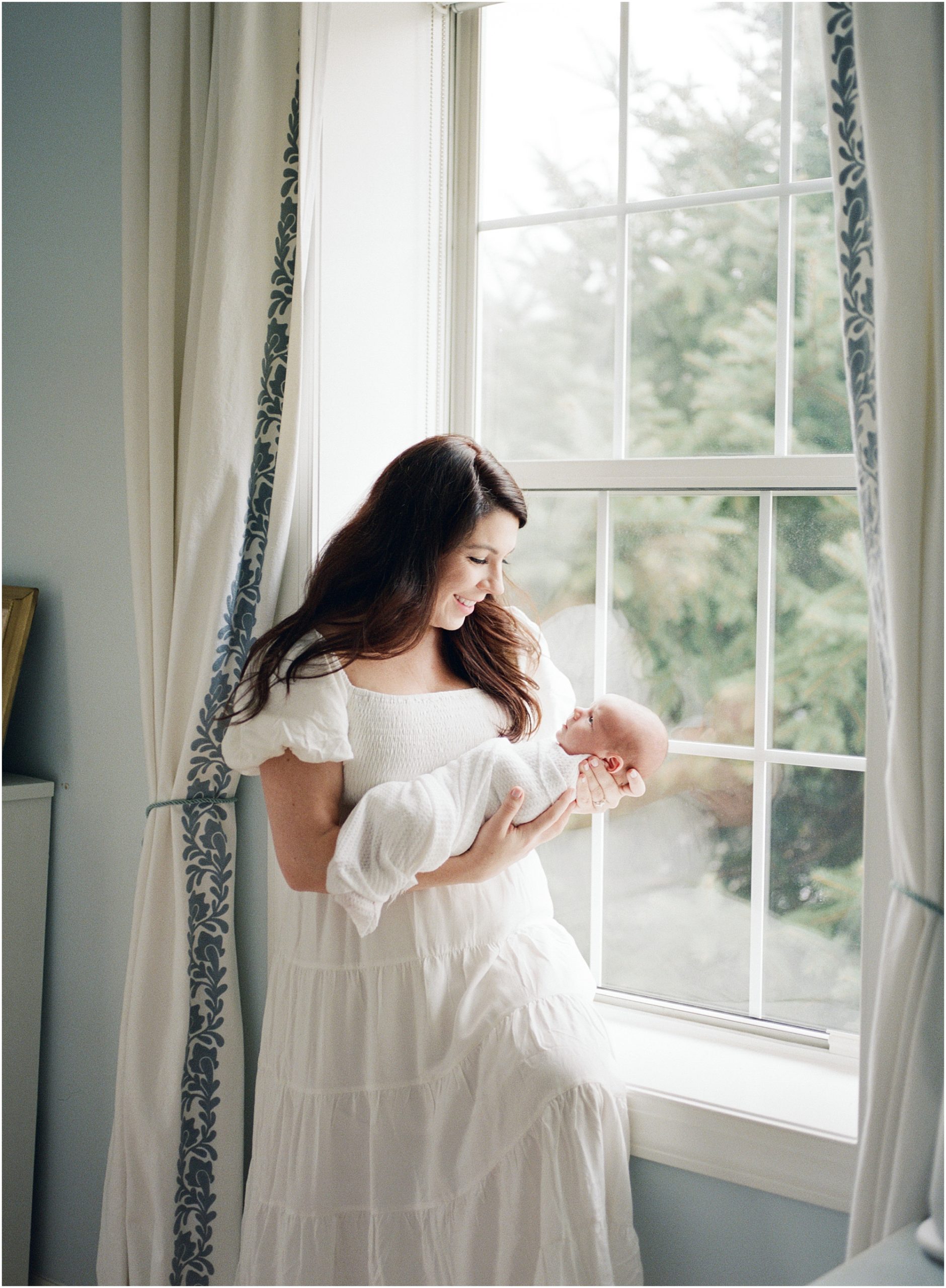 mother with newborn sitting by window film photographer dc newborn photo